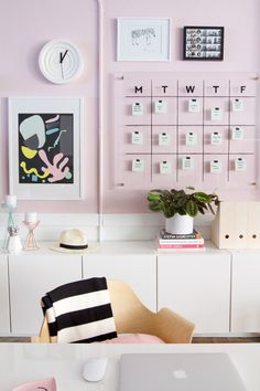 a white desk topped with a laptop computer sitting next to a wall mounted calendars