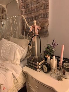 a white bed topped with lots of pillows next to a night stand filled with books