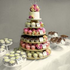 a tiered cake with cupcakes on it and other desserts around it