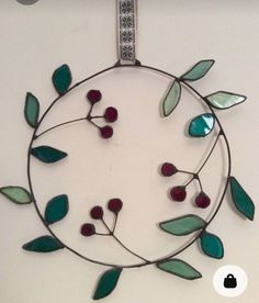 a circular metal wall hanging with leaves and berries