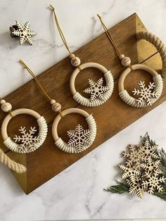 three pairs of wooden hoop earrings with snowflakes hanging from them on a wood board