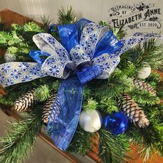 a christmas wreath with pine cones and blue ribbon