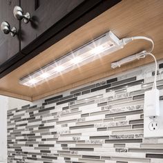 a light that is on above a sink in a room with tile walls and cabinets