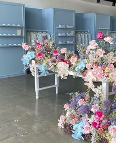 a table with flowers on it in a room filled with shelves and shelvings