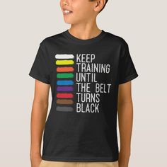 a young boy wearing a t - shirt that says keep training until the belt turns black