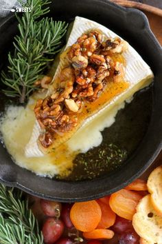 a fish fillet in a cast iron skillet surrounded by fruit and bread on a wooden table