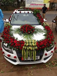 a white car decorated with red roses and greenery