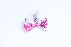 a pink and white flowered bow tie laying on top of a white tablecloth