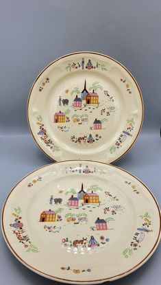 two plates with designs on them sitting next to each other in front of a gray background