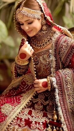 a woman in a red and gold bridal gown with jewelry on her head,