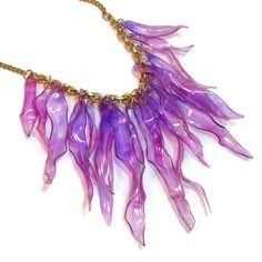 a purple necklace is hanging from a gold chain