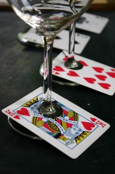 two wine glasses sitting next to each other on top of a table with playing cards