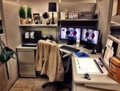 an office cubicle with two computer monitors and a keyboard