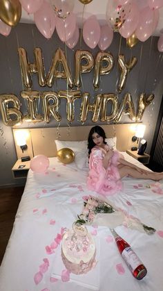 a woman laying on top of a bed with balloons and confetti