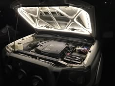 an open car trunk with the hood up and its engine in it's center