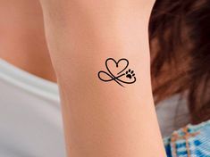 a woman's arm with a tattoo on it that has a dog paw and heart