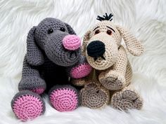 two crocheted dogs sitting next to each other on a white fur covered surface