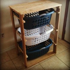 three plastic baskets stacked on top of each other in a wooden shelf next to a tiled floor