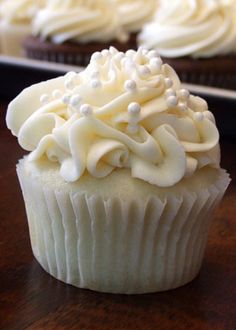 two cupcakes with white frosting on top are sitting side by side in front of each other