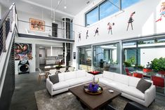 a living room filled with white couches and chairs next to an open floor plan