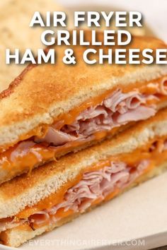 a grilled ham and cheese sandwich cut in half on a plate with the words air fryer grilled ham and cheese