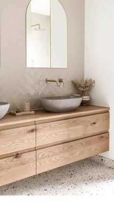 two sinks are on top of a wooden cabinet in the bathroom, while a mirror hangs above them