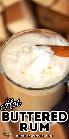 hot buttered rum in a glass mug with whipped cream and cinnamon on the rim