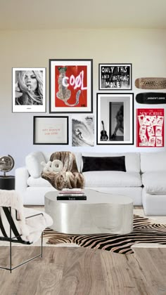 a living room filled with white furniture and pictures on the wall