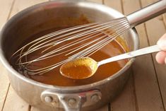 a person whisk something in a saucepan on a wooden table with a spoon