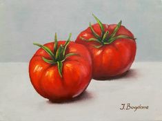 two red tomatoes sitting on top of a white surface