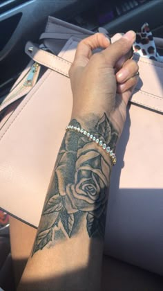 a woman's arm with a rose tattoo on it, sitting in a car