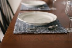 a table set for two with wine glasses and silverware on the placemats