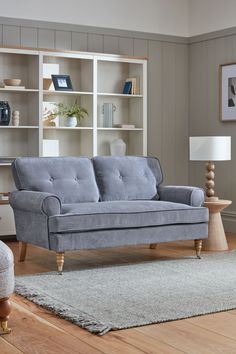 a living room with a gray couch and white bookshelf