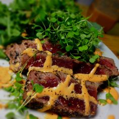 a plate topped with meat and greens covered in cheese sauce on top of lettuce