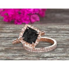 an engagement ring with a black diamond surrounded by white and pink diamonds on a wooden surface