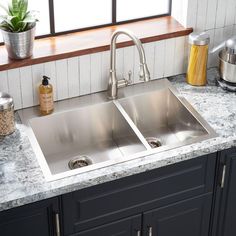 two stainless steel sinks in a kitchen with granite counter tops