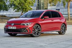 a red volkswagen golf gt line parked in front of a building