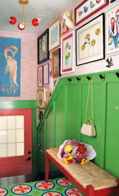 a green wall with pictures on it and a bench in front of the entry way