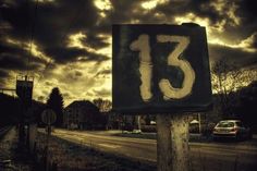 a street sign with the number thirteen painted on it in front of a cloudy sky