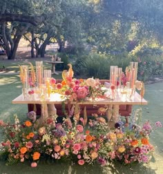 an arrangement of flowers and vases on a table in the middle of a field