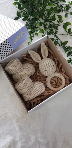 two stuffed animals in a box on a white surface next to a plant and card