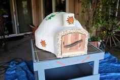 a clock that is sitting on top of a blue table cloth in front of a house