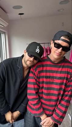 two men standing next to each other wearing hats