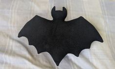 a black bat shaped object sitting on top of a bed