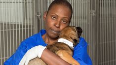 a woman holding a dog in her arms and looking at the camera with an intense look on her face