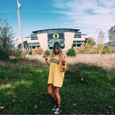 a woman standing in front of a stadium holding her hand out to the side while wearing sunglasses