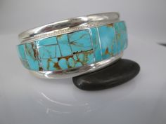 Native American Turquoise Cuff Bracelet. A gorgeous solid sterling silver and genuine turquoise cuff. The beautiful turquoise is of a rich bright blue with swirls of caramel color matrix, from the Royston Mine in Nevada. Inlaid design handcrafted by Zuni silversmiths Rickell & Glendora Booqa, and hallmarked with their RGB and sterling. This beauty measures 1 1/16" at its widest, tapers in back for a comfort fit. It is 5 1/2" around the inside PLUS a 1 3/8" gap. Weighs a hefty 41.7gms. This is gr Turquoise Cuff Bracelet With Polished Finish, Turquoise Sterling Silver Cuff Bracelet With Inlay, Sterling Silver Turquoise Cuff Bracelet With Inlay, Southwestern Multi-stone Bangle Cuff Bracelet, Southwestern Adjustable Multi-stone Cuff Bracelet, Adjustable Hand-tooled Turquoise Cuff Bracelet, Unique Turquoise Nickel-free Cuff Bracelet, Native American Turquoise, Turquoise Bracelet Cuff