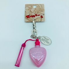 a pink heart shaped bottle is attached to a key chain with a coin hanging from it