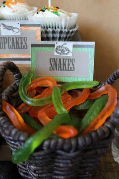 some cupcakes are sitting in a basket with green and orange peppers on it