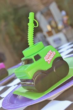 a green toy truck sitting on top of a purple and purple plate with a fork in it's mouth